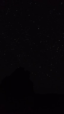 the night sky with stars above a mountain