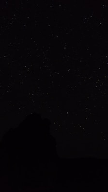 the night sky with stars above a mountain