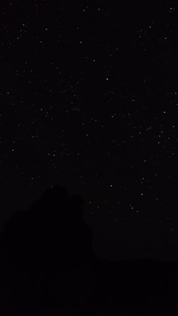 the night sky with stars above a mountain