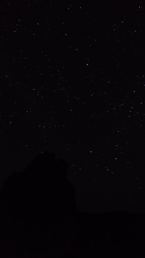 the night sky with stars above a mountain