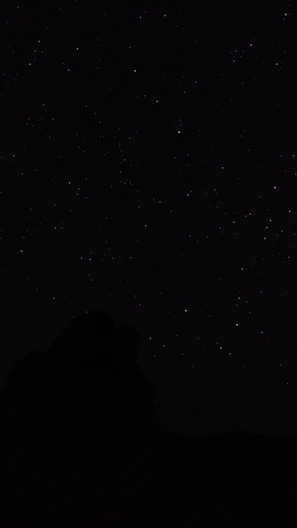 the night sky with stars above a mountain