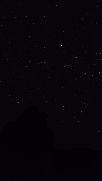the night sky with stars above a mountain
