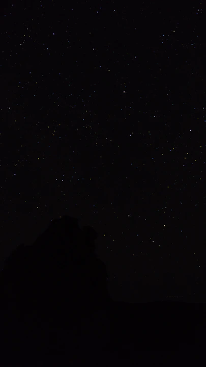 the night sky with stars above a mountain