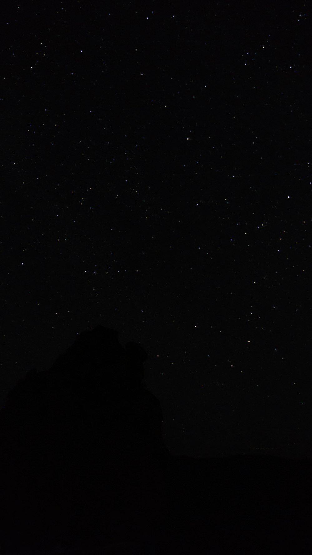 the night sky with stars above a mountain