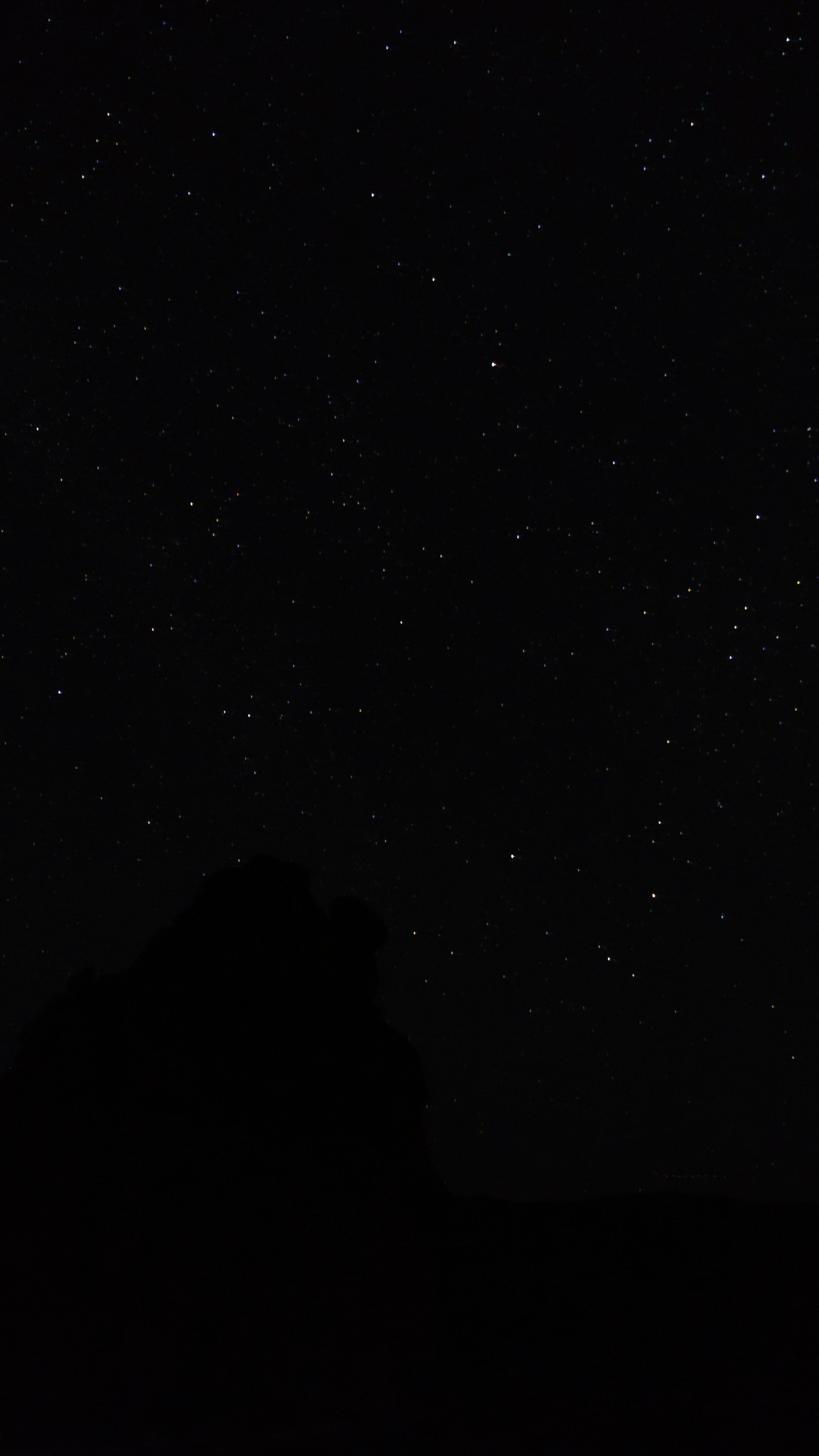 the night sky with stars above a mountain