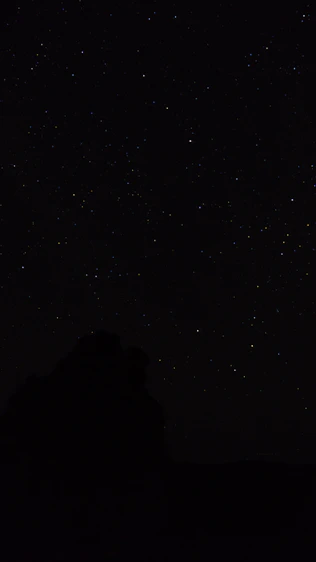 the night sky with stars above a mountain