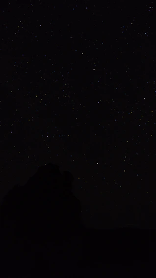 the night sky with stars above a mountain
