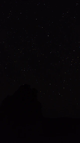 the night sky with stars above a mountain