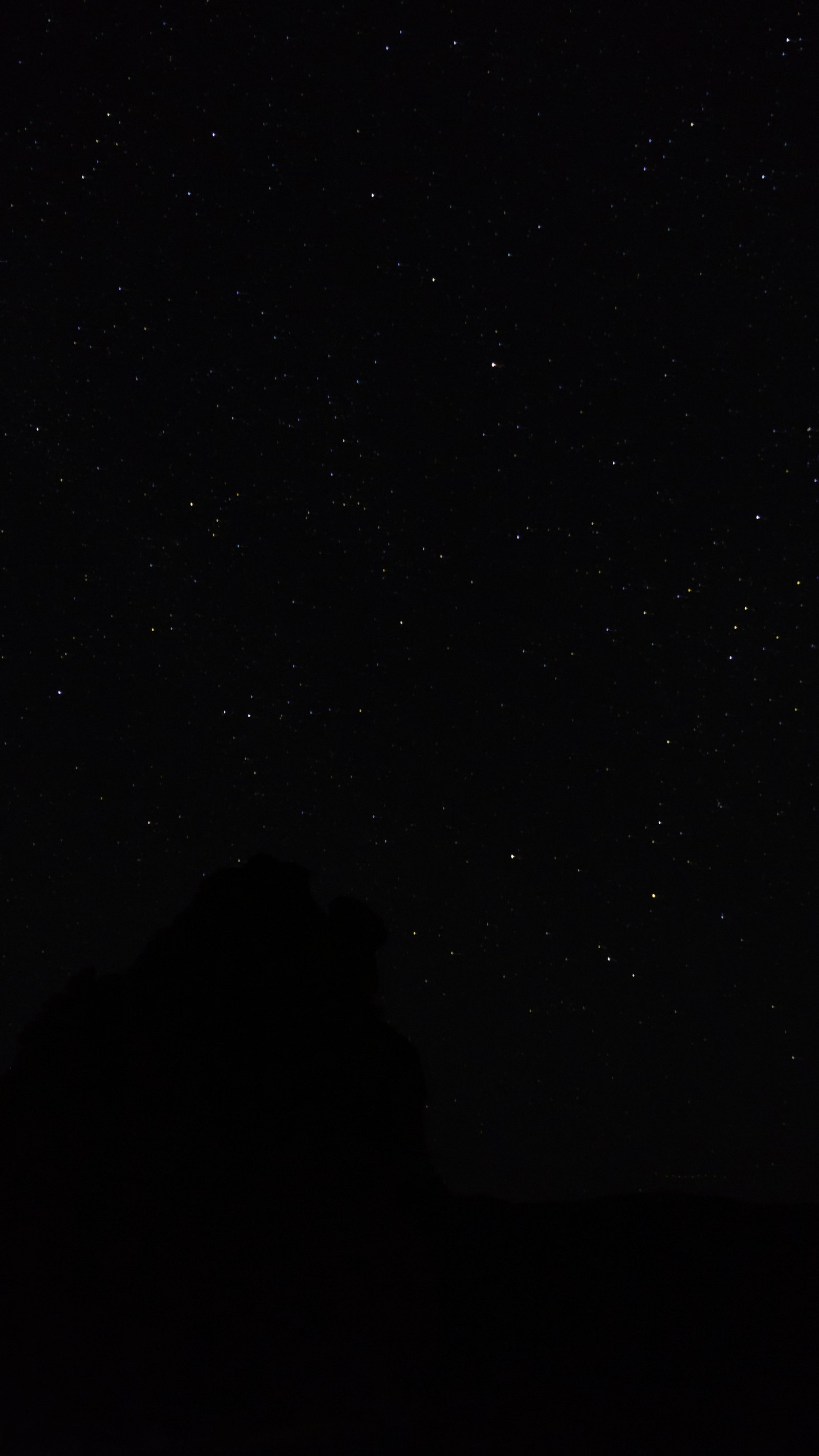 The night sky with stars above a mountain