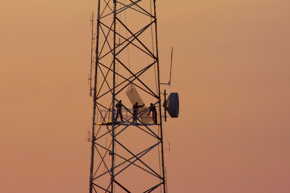 três pessoas em pé na torre do guindaste