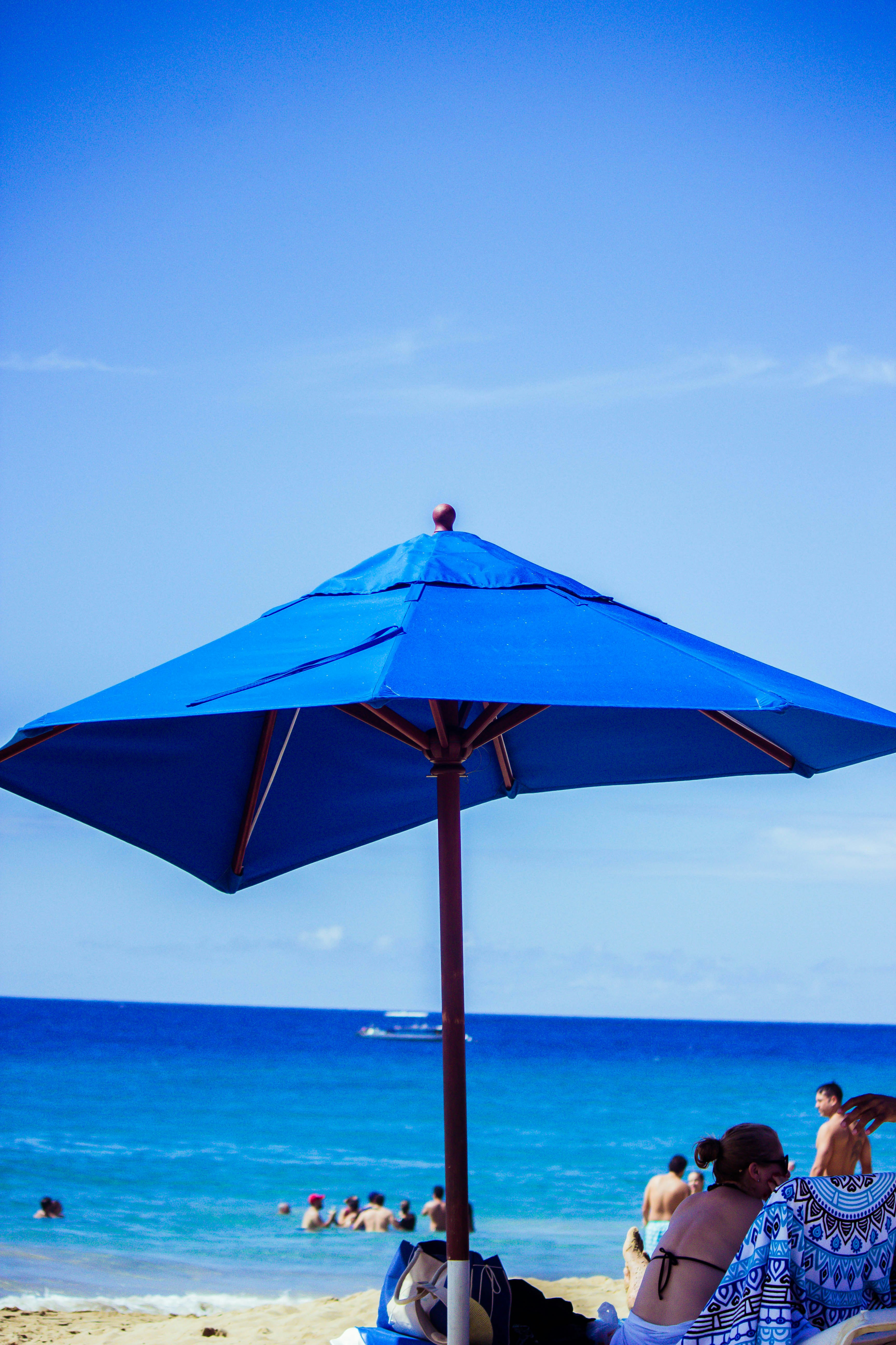 woman under blue parasol during daytime
