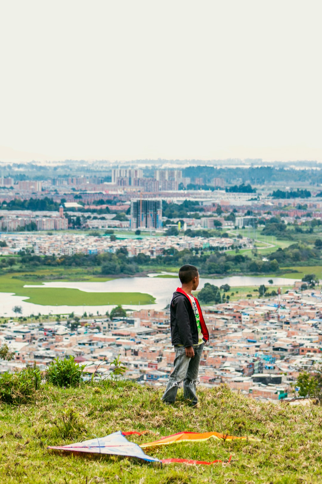 boy standing on the grass field watching the village