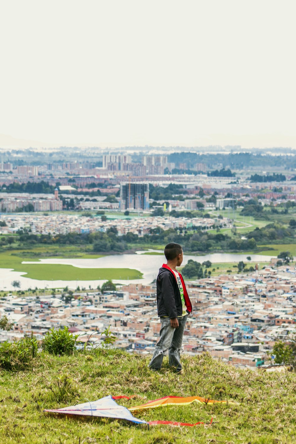 boy standing on the grass field watching the village