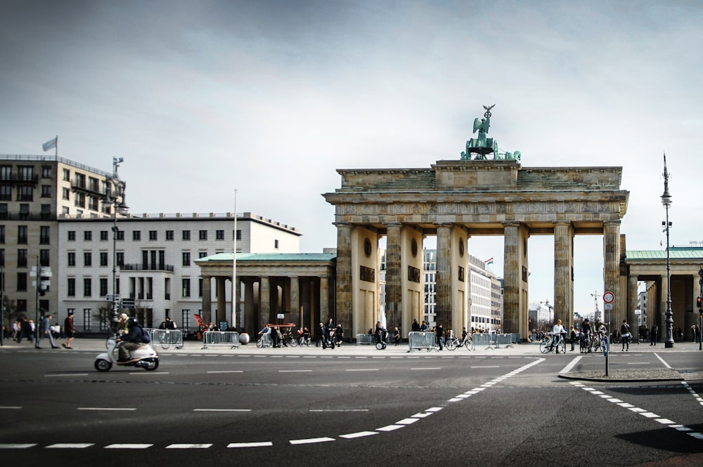 people walking beside beige concrete arch