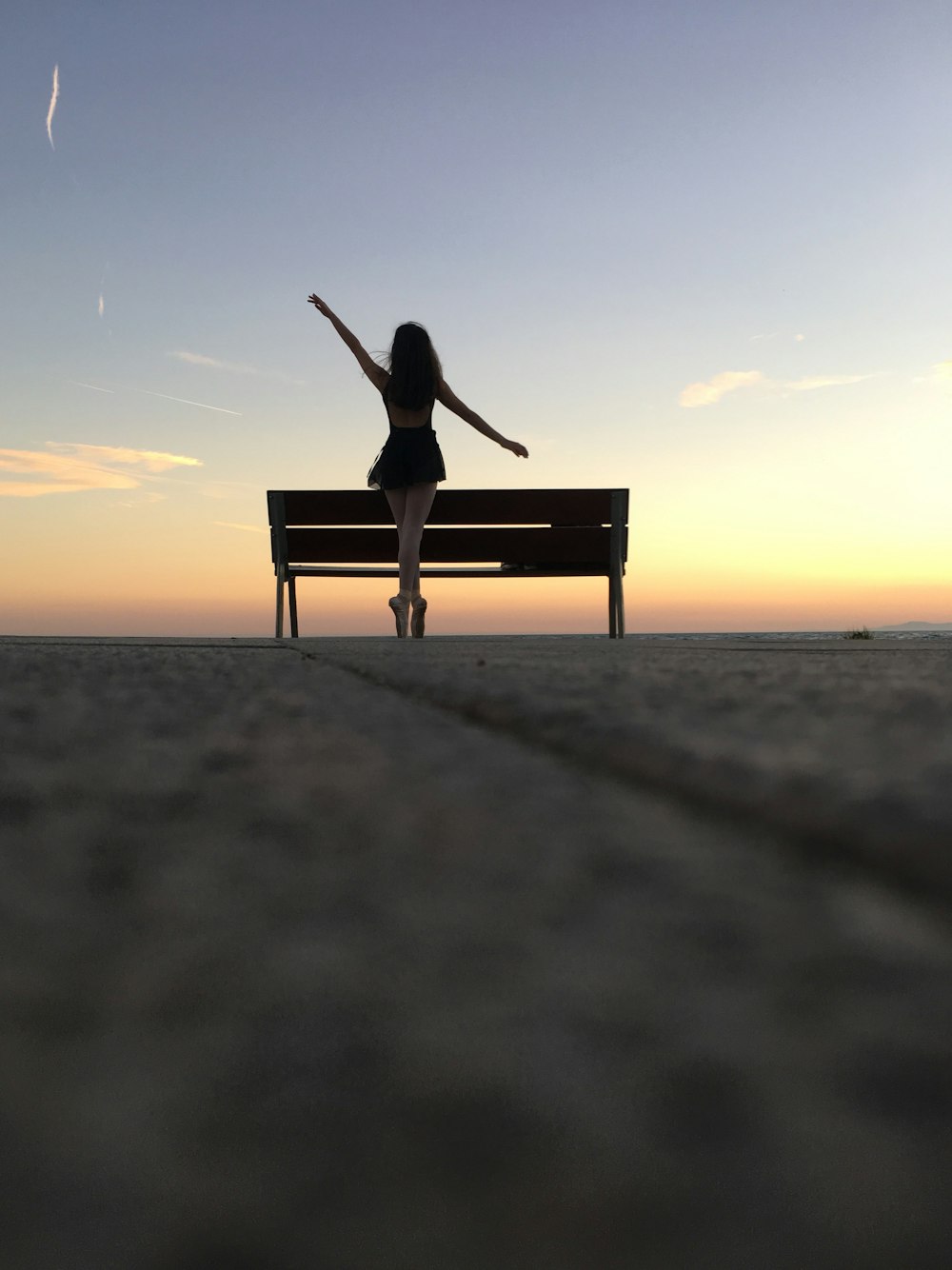 silhouette photography of woman standing on bench