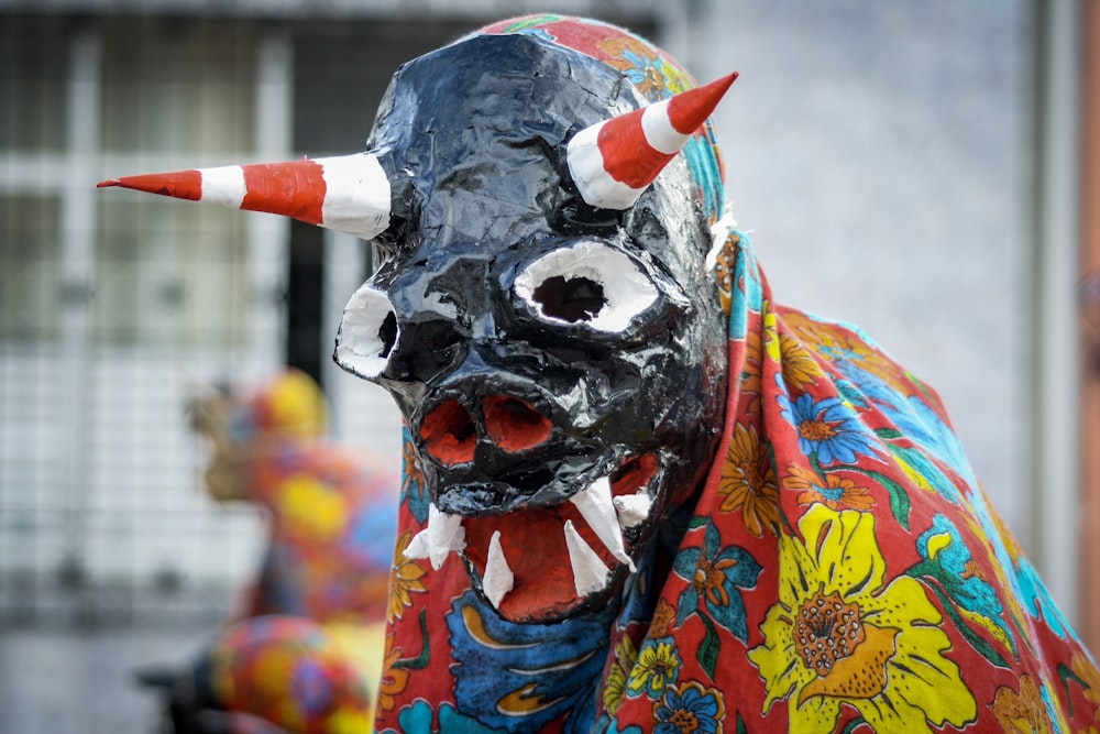person wearing monster mask covered with yellow and red floral cape