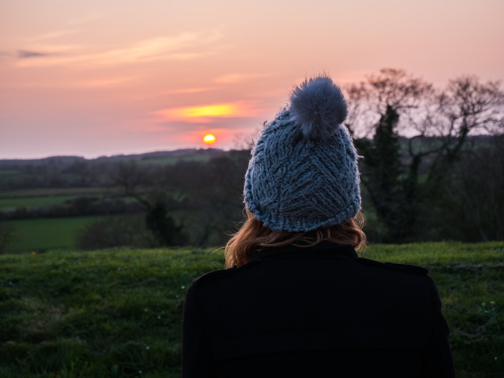 woman facing leafless tree during golden hour