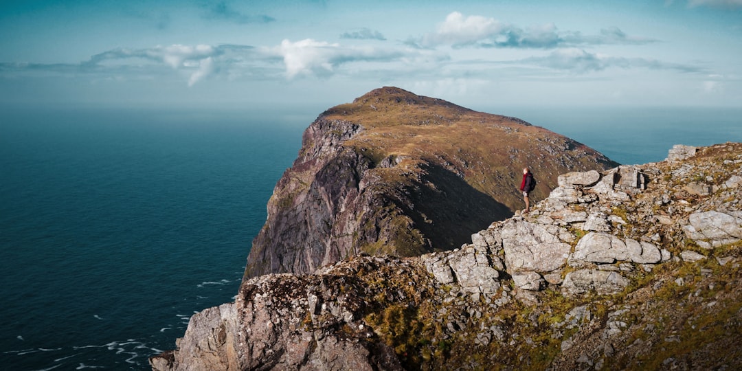 sea cliff under cloudy blue sky during daytime