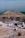 A large industrial quarry site featuring mounds of gravel and dirt, with several pieces of machinery positioned around the area. There are pathways through the site, piles of rock, and various metal structures.