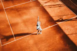 Young tennis player practicing serves on a sunny outdoor court.