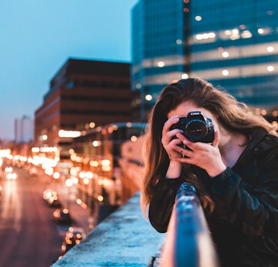 woman using black camera outdoors