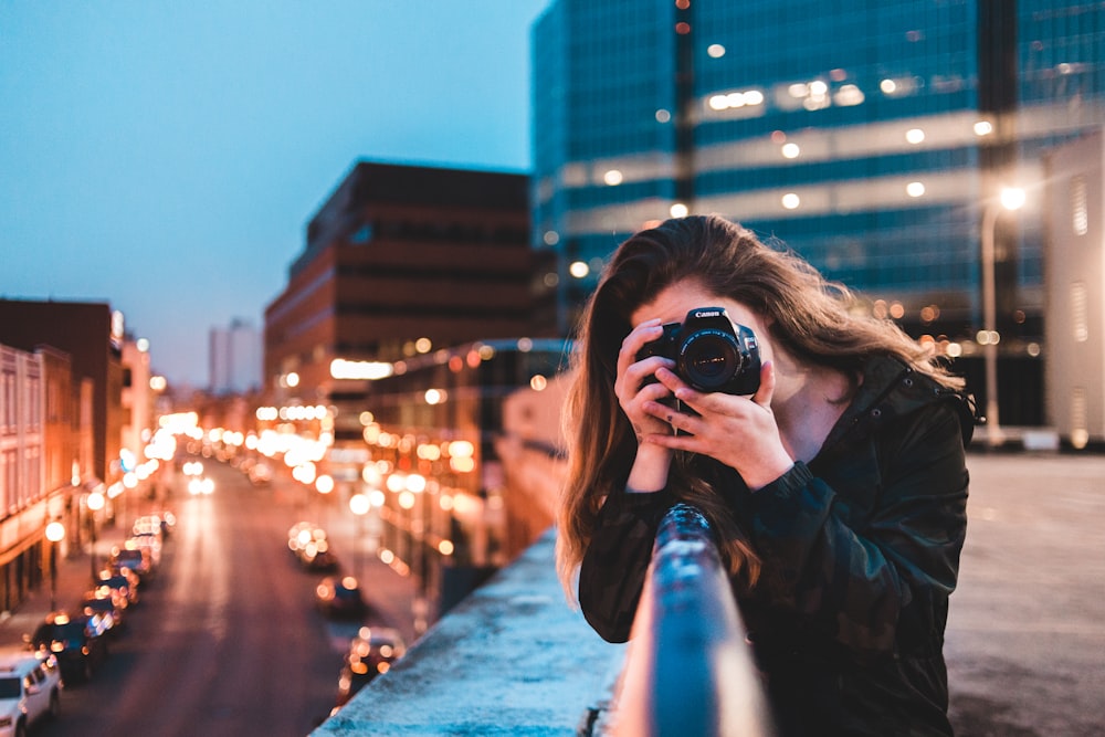 woman using black camera outdoors