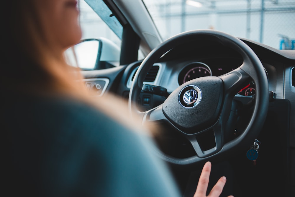 woman sitting inside vehicle holding vehicle wheel