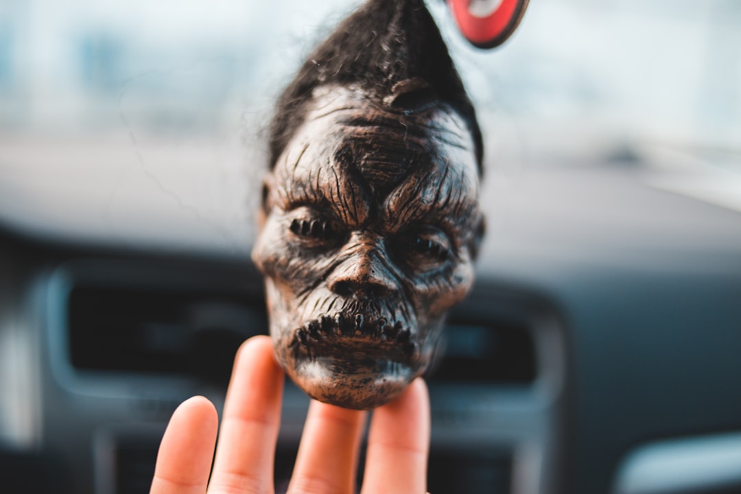 person holding a doll head decor in car