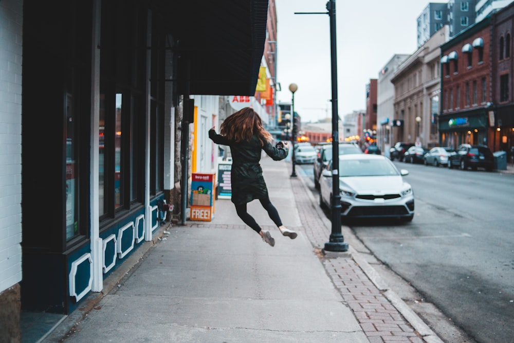 woman jumping infront of parked white vehicle