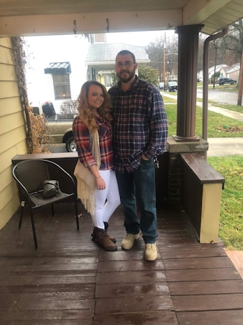 Smiling couple standing outside their home, relieved after pest treatment.