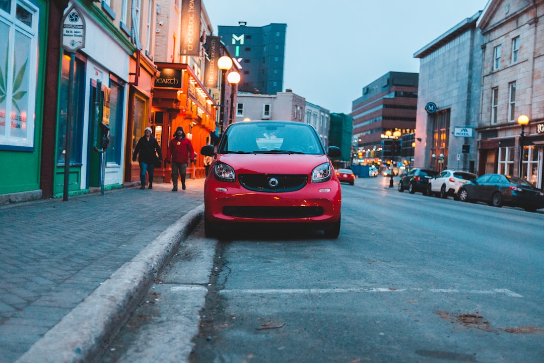 red car parking near road viewing city with high-rise buildings