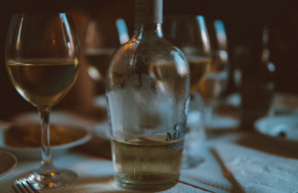 half-filled liquor bottle on wine glasses