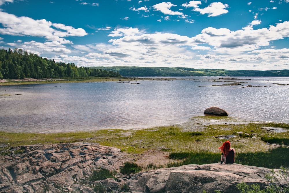 woman sitting on rock near river