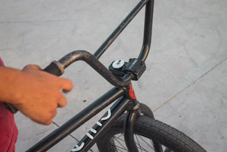 Close-up of a child's hands gripping the rounded handlebars of a Tinywheelz bike with a soft neutral background.