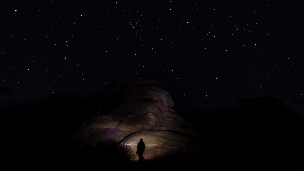 une personne debout dans le noir sous un ciel nocturne