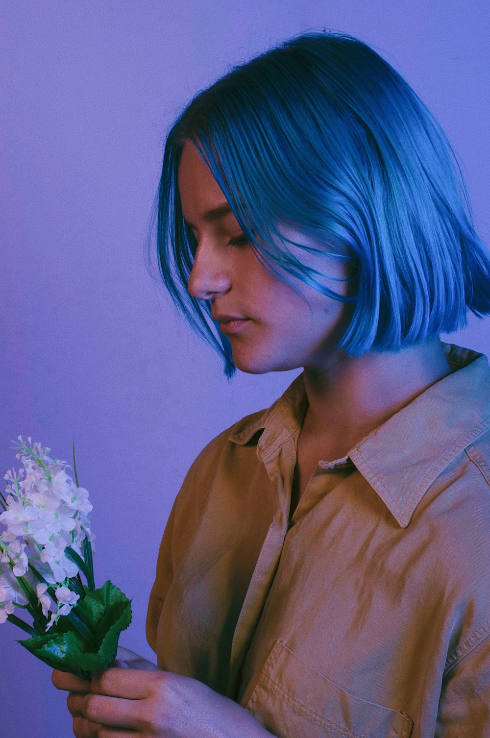 woman wearing blue button-up shirt holding white flowers