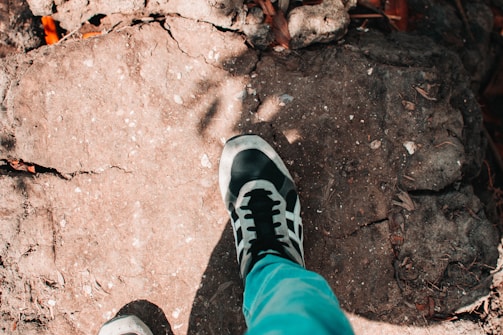 Close-up of a sleek, flexible Malik LLC athletic shoe mid-stride on a rocky trail.