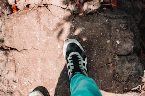 Close-up of gold-accented sneakers stepping on a cracked pavement.