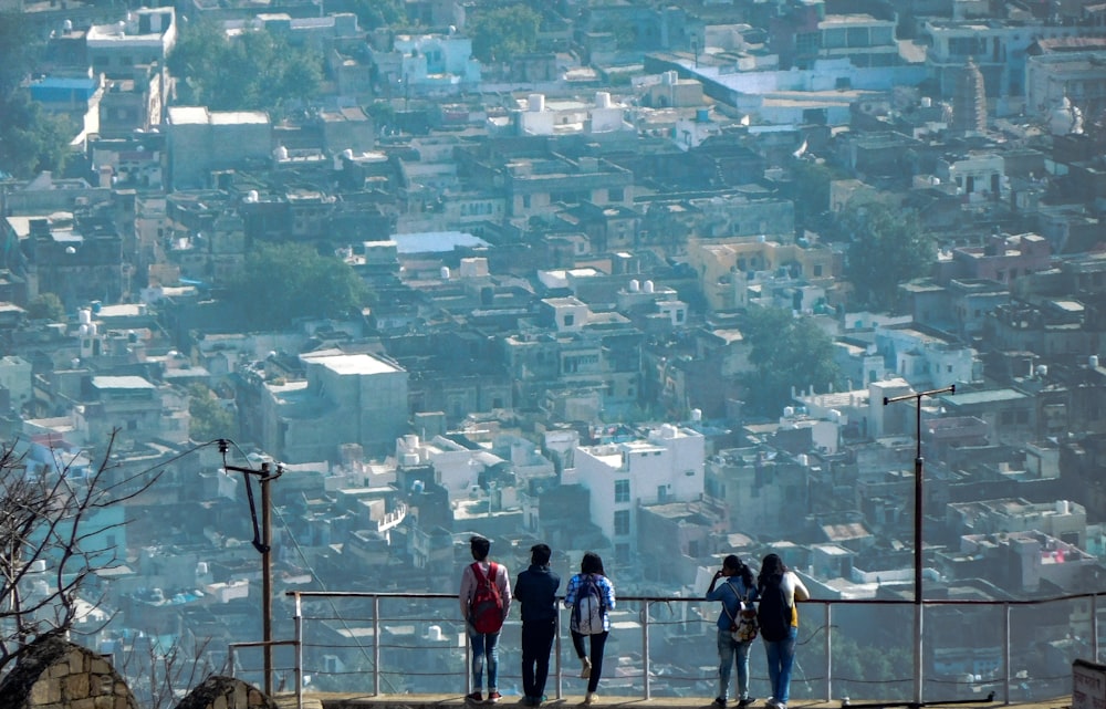 five person standing while facing the areal view of the city
