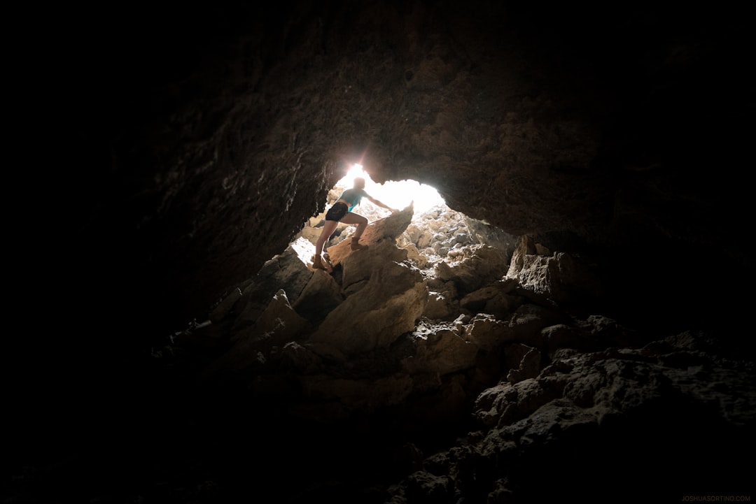 person standing on rocks near cave