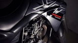 Close-up view of a motorcycle with a focus on its sleek black design featuring bold angular patterns and the label '660R Fuel Injection' highlighted in red. The image emphasizes the mechanical components, showcasing the engine and part of the exhaust.