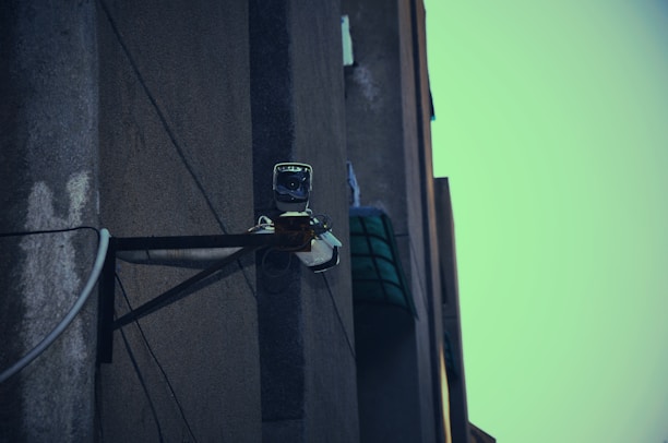 Technician installing a security camera on a residential building exterior.