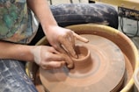 Close-up of a student’s hands skillfully centering clay on a pottery wheel.
