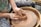 Hands are skillfully shaping clay on a spinning pottery wheel. The focus is on the creation of a clay pot, with the person's hands covered in moist clay, emphasizing the tactile nature of pottery.