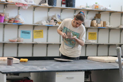 A joyful moment as an artisan inspects a freshly glazed ceramic piece in the studio.