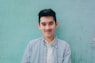 man wearing blue white stripe shirt leaning on the wall