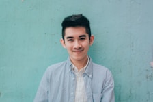 man wearing blue white stripe shirt leaning on the wall