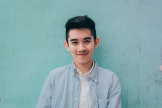 man wearing blue white stripe shirt leaning on the wall