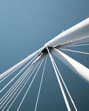 Close-up of a bridge's suspension cables against a bright blue sky.