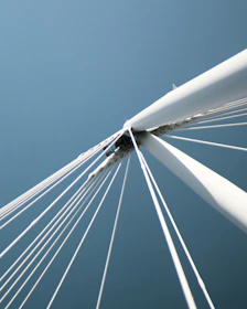 Close-up of a bridge's suspension cables against a bright blue sky.